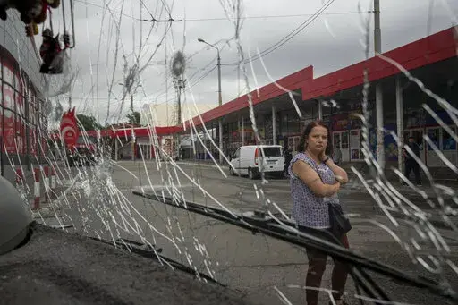 A woman looks at a trolleybus damaged by Russian shelling at Barabashovo market in Kharkiv, Ukraine, Thursday, July 21, 2022. (AP Photo/Evgeniy Maloletka)