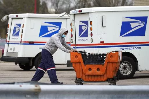 A United States Postal Service employee works outside a post office in Wheeling, Ill., Dec. 3, 2021.  The nation’s major shipping companies are in the best shape to get holiday shoppers’ packages delivered on time since the start of the pandemic, suggesting a return to normalcy. (AP Photo/Nam Y. Huh, File)