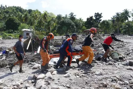Rescuers carry a body at Maguindanao's Datu Odin Sinsuat town, southern Philippines on Sunday Oct. 30, 2022. Victims of a huge mudslide set off by Tropical Storm Nalgae in a coastal Philippine village that had once been devastated by a killer tsunami mistakenly thought a tidal wave was coming and ran to higher ground toward a mountain and were buried alive, an official said Sunday. (AP Photo)