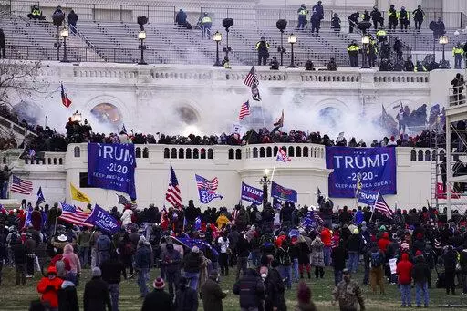 Violent insurrectionists loyal to President Donald Trump storm the Capitol, Jan. 6, 2021, in Washington. An Ohio man charged with stealing a coat rack from the U.S. Capitol doesn't deny that he joined the mob that stormed the building last year. But a lawyer for Capitol riot defendant Dustin Thompson vows to show that former President Donald Trump abused his power to authorize the attack on Jan. 6. (AP Photo/John Minchillo, File)