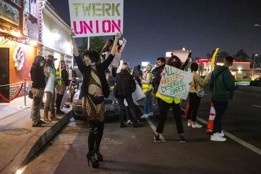 A protester identified as "Reagan" holds a sign outside the Star Garden Topless Dive Bar on Saturday, March 26, 2022 in the North Hollywood area of Los Angeles. Dancers at the bar, who have for 15 months been seeking safer workplace conditions, better pay and health insurance, among other benefits, are poised to become the only unionized group of strippers in the U.S. (Francine Orr/Los Angeles Times via AP)