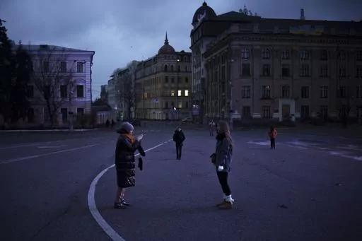 People walk and take photos on a street closed for cars at dusk in Kyiv, Ukraine, Sunday, Nov. 26, 2023. (AP Photo/Felipe Dana)