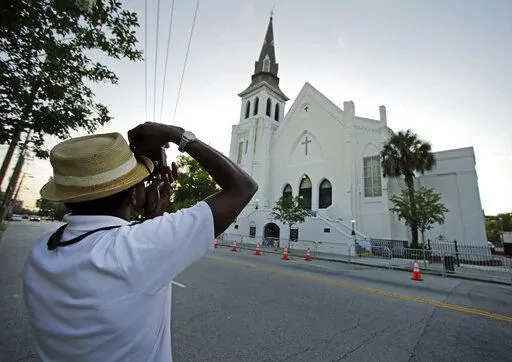 FILE _ This file photo shows Ausar Vandross taking a photo of Mother Emanuel AME Church in Charleston, S.C., on Thursday, June 16, 2016. The church is among those that have been assisted by a fund to help historic Black churches, and a new, $20 million donation will help additional ones. (AP Photo/Chuck Burton)