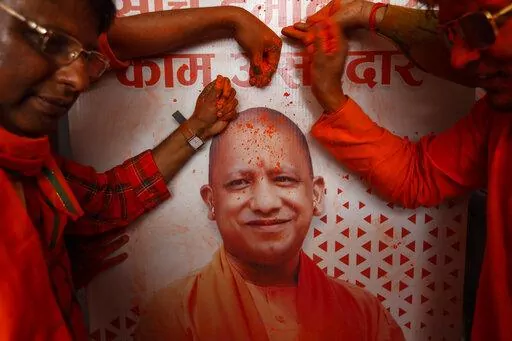 Bharatiya Janata Party (BJP) workers put colored powder on a photograph of incumbent chief minister Yogi Adityanath as they celebrate early leads for the party as election officials count votes after Uttar Pradesh state elections in Lucknow, India, Thursday, March 10, 2022. India's election authority started counting votes Thursday in five states' elections that are a crucial test for Prime Minister Narendra Modi’s Hindu nationalist Bharatiya Janata Party before national elections in 2024.All 