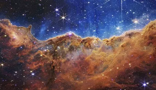 This image released by NASA on Tuesday, July 12, 2022, shows the edge of a nearby, young, star-forming region NGC 3324 in the Carina Nebula. Captured in infrared light by the Near-Infrared Camera (NIRCam) on the James Webb Space Telescope, this image reveals previously obscured areas of star birth, according to NASA. (NASA, ESA, CSA, and STScI via AP)