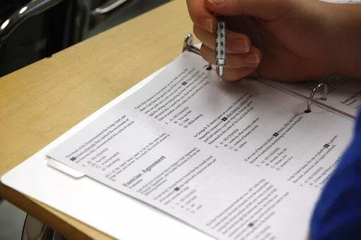 In this photo taken Jan. 17, 2016, a student looks at questions during a college test preparation class at Holton Arms School in Bethesda, Md.  The SAT exam will move from paper and pencil to a digital format, administrators announced Tuesday, Jan. 25, 2022, saying the shift will boost its relevancy as more colleges make standardized tests optional for admission.   (AP Photo/Alex Brandon)