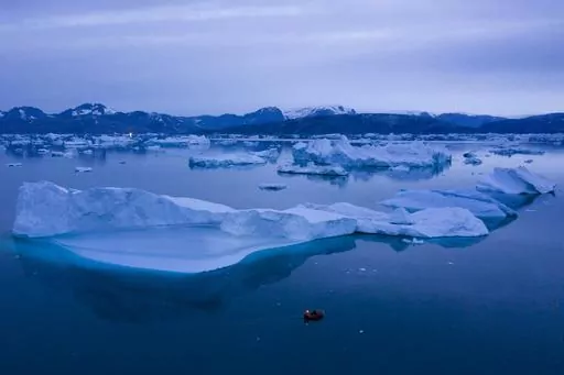 A boat navigates at night next to large icebergs near the town of Kulusuk, in eastern Greenland on Aug. 15, 2019. A new massive study finds that Greenland and Antarctic ice sheets are now losing more than three times as much ice a year as they were 30 years ago. (AP Photo/Felipe Dana, File)
