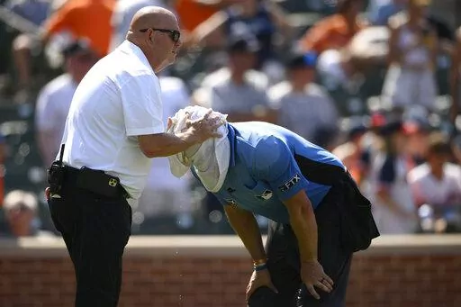 Baltimore Orioles head trainer Brian Ebel, left, helps home plate umpire Scott Barry get relief with a wet towel around his head after the sixth inning of a baseball game between the Orioles and the New York Yankees, Sunday, July 24, 2022, in Baltimore. The Yankees won 5-0. (AP Photo/Nick Wass)