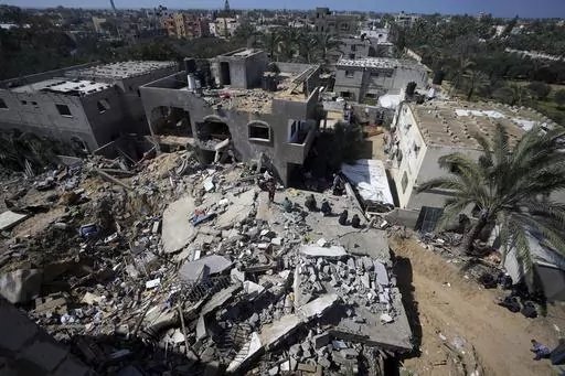 Palestinians look at destruction after an Israeli airstrike on a residential building of the Ganan family in Deir al Balah, Gaza Strip, Thursday, March 7, 2024. (AP Photo/Adel Hana)