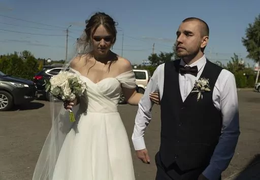 Bride Vladislava Ryabets, left, helps groom Ivan Soroka, right, to walk during their wedding day in Kyiv, Ukraine on Saturday, Sept. 9, 2023. Shrapnel blinded Soroka permanently on Aug. 2, 2022 when Russian mortar fire struck his retreating unit near Bakhmut during the war's longest and bloodiest battle. Despite Soroka's injury the couple has been determined to move forward. (AP Photo/Bela Szandelszky)