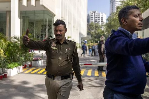 A police officer and a private security guard ask journalists to leave from the gate of a building housing BBC office in New Delhi, India, Tuesday, Feb. 14, 2023. Officials from India's Income Tax department began conducting searches Tuesday at the BBC's offices in the capital, New Delhi, three of the broadcaster's staff members told the Associated Press. (AP Photo/Altaf Qadri)