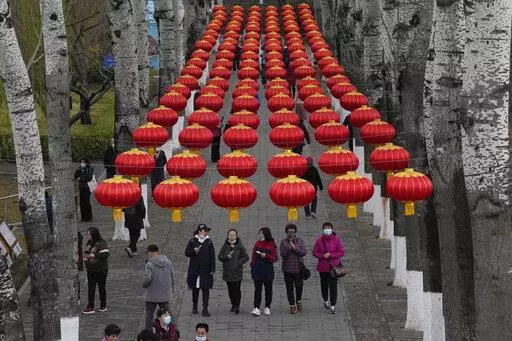 Visitors, some wearing masks, walk through a park on Wednesday, March 30, 2022, in Beijing. China's case numbers in its latest infection surge are low compared with other major countries. But the ruling Communist Party is enforcing a "zero tolerance" strategy aimed at isolating every infected person. (AP Photo/Ng Han Guan)