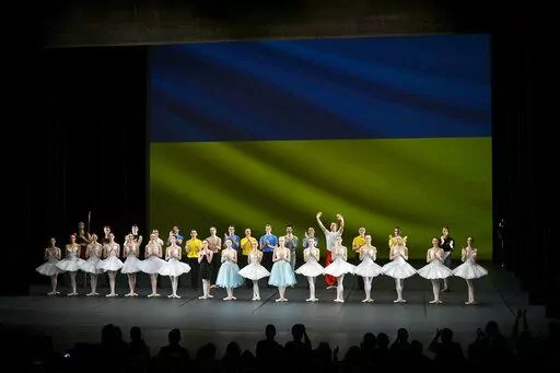 Ukrainian dancers of the Kyiv City Ballet company acknowledge applause in front of Ukrainian flag projected onto a screen at the end of a performance, at the Theatre de Chatelet, in Paris, Tuesday, March 8, 2022. The Kyiv City Ballet danced to a full house in Paris for the last show of a French tour that has left the company stranded after the war broke out in Ukraine. They described being physically and emotionally exhausted. Being given the opportunity to train and dance was for many a chance 