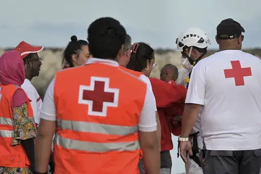 A baby is carried by members of the Red Cross in the port of La Restinga at El Hierro in the Canary Islands on Saturday, June 6, 2024, after being rescued by the Spanish Sea Rescue. Spain's Canary Islands are struggling to deal with thousands of teenagers and children traveling alone to the archipelago from Senegal, Mali, and other African nations. (Europa Press via AP)