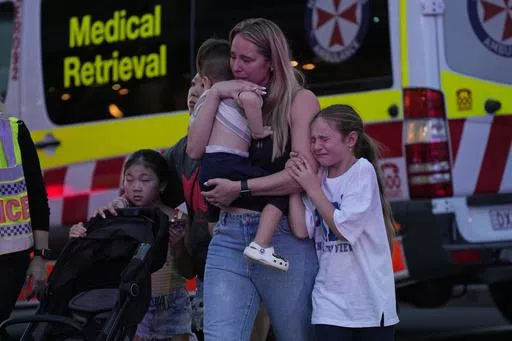 People are led out from the Westfield Shopping Centre where multiple people were stabbed in Sydney, Saturday, April 13, 2024. A man stabbed six people to death at the busy Sydney shopping center Saturday before he was fatally shot, police said. (AP Photo/Rick Rycroft)