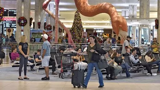 Holiday travelers pass by "Phoebe" the Flamingo at the Tampa International Airport, Friday, Dec. 22, 2023, in Tampa, Fla. Conditions were mostly nice for travelers flying ahead of and on Christmas Day this year, but some naughty disruptions plagued those flying with Southwest Airlines again this year. By midday Monday, Dec. 25, only 138 flights within, into or out of the U.S. had been canceled and 1,366 were delayed, according to FlightAware, a tracking website. (AP Photo/Chris O'Meara, File)