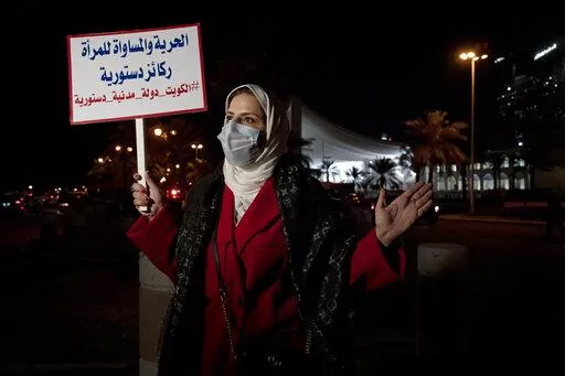 Mashael al-Shuwaihan, who sits on the board of Kuwait's Women's Cultural Society, speaks during an interview, at a protest outside Kuwait's National Assembly, in Kuwait City, Monday, Feb. 7, 2022. Her placard reads: "Freedom and equality for women are constitutional pillars." Women might be progressing across the Arab world, but in Kuwait, the guardians of conservative morals have increasingly cracked down on their rights in recent months, prompting activists to take to the streets last week. (A