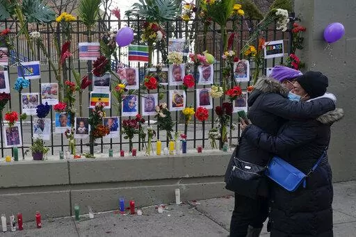 People hug after viewing a memorial for the victims of an apartment building fire near the site of the fire in the Bronx borough of New York, Thursday, Jan. 13, 2022.  Many of the victims of New York City’s deadliest fire in years are still awaiting burial after funerals began with services for two children killed by Sunday’s blaze in a Bronx apartment building. (AP Photo/Seth Wenig)