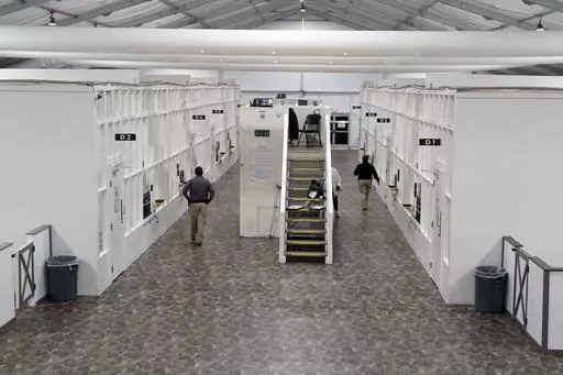 Agents walk among rooms at a Border Patrol holding facility on Dec. 15, 2023, in Tucson, Ariz. U.S. asylum officers were instructed nearly a year ago to apply a higher screening standard on people who cross the border illegally to claim asylum after passing through another country. But they are too understaffed to have much impact. (AP Photo/Gregory Bull, File)