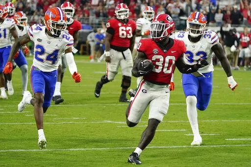 Georgia running back Daijun Edwards (30) runs for a 22-yard touchdown past Florida cornerback Avery Helm (24) and defensive lineman Princely Umanmielen (33) during the second half of an NCAA college football game Saturday, Oct. 29, 2022, in Jacksonville, Fla. (AP Photo/John Raoux)