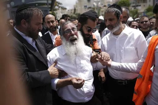 Ultra-Orthodox Jewish mourners encircle a man overcome with grief at the funeral for Yonatan Havakuk and Boaz Gol, a day after they were killed in a stabbing attack in Elad, Israel, Friday, May 6, 2022. Israeli security forces waged a massive manhunt Friday for two Palestinians suspected of carrying out the stabbing attack on Thursday near Tel Aviv that left three Israelis dead. (AP Photo/Ariel Schalit)