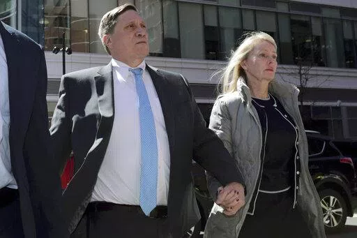 John Wilson arrives at federal court, with his wife Leslie, on April 3, 2019 to face charges in a nationwide college admissions bribery scandal in Boston. Wilson, a former Staples Inc. executive who was convicted of trying to bribe his children's way into USC, Harvard and Stanford, is scheduled to be sentenced on federal charges Wednesday Feb. 16, 2022. (AP Photo/Charles Krupa, File)