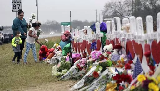 Christina Osborn and her children Alexander Osborn and Bella Araiza visit a makeshift memorial for the victims of the shooting at Sutherland Springs Baptist Church, Nov. 12, 2017, in Sutherland Springs, Texas. The Justice Department said Wednesday, April 5, 2023, that it has tentatively settled a lawsuit over the 2017 mass shooting at a Texas church that will pay victims and their families more than $144 million. (AP Photo/Eric Gay, File)
