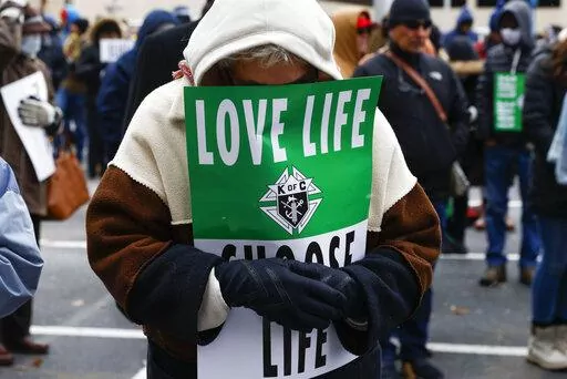 A marcher prays ahead of the North Texas March for Life, celebrating the passage and court rulings upholding the Texas law known as Senate Bill 8, on Saturday, Jan. 15, 2022, in Dallas. Abortion isn't taking center stage in Texas' first-in-the-nation primary. The March 1, 2022 primary will mark six months that Texas clinics have operated under a law that bans abortion after roughly six weeks of pregnancy.    (Shafkat Anowar/The Dallas Morning News via AP, File)