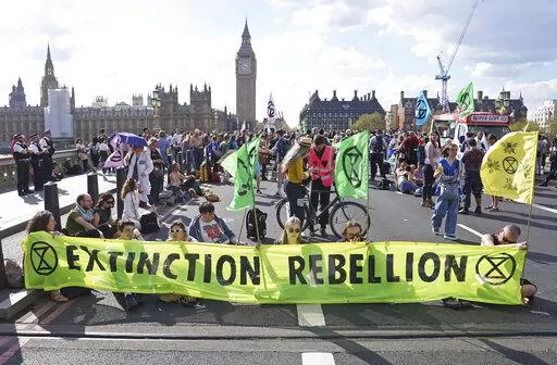 Demonstrators take part in an Extinction Rebellion protest on Westminster Bridge in London, Friday, April 15, 2022. Climate-change protesters have snarled traffic by blocking four London bridges. Cars and red double-decker buses backed up along roads as hundreds of Extinction Rebellion activists occupied London’s Waterloo, Blackfriars, Lambeth and Westminster bridges, calling for an end to new fossil fuel investments. (Stefan Rousseau/PA via AP)