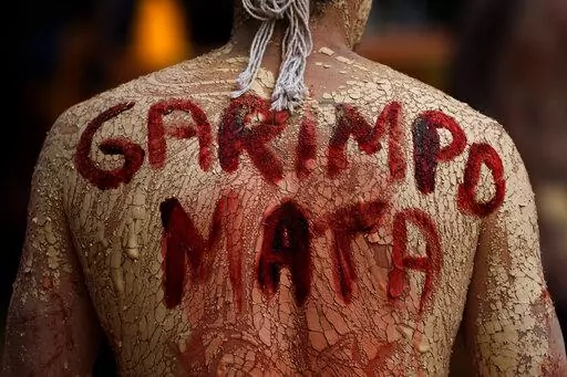 An Indigenous man with a phrase in Portuguese painted on his back that translates to "Mining Kills," participates in a protest against the increase of mining activities that are encroaching on his land, in front of the Ministry of Mines and Energy, in Brasilia, Brazil, Monday, April 11, 2022. A fast-expanding network of antennae is empowering Indigenous groups to use phones, video cameras and social media to galvanize the public and pressure authorities to respond swiftly to threats from gold mi