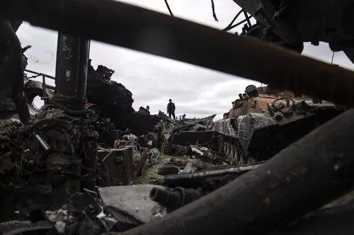 A local man stands atop of destroyed Russian armoured vehicles in Bucha, Ukraine, Tuesday, April 19, 2022. (AP Photo/Evgeniy Maloletka)