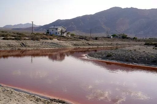 FILE— Clouds and nearby mountains are reflected in a polluted canal, once used as a boating dock, along the Salton Sea in Desert Shores, Calif., Wednesday, July 14, 2021. President Joe Biden on Tuesday, Feb. 22, 2022, pointed to plans to extract lithium from geothermal wastewater around the sea as an example of the Unites States' efforts to compete with China and other nations when it comes to domestic lithium production. The metal is a key element in rechargeable batteries, such as those used