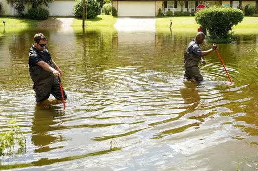 Hinds County Emergency Management Operations deputy director Tracy Funches, right, and operations coordinator Luke Chennault, wade through flood waters in northeast Jackson, Miss., on Aug. 29, 2022, as they check water levels. A federal agency has set aside money to help guard Mississippi’s capital city and surrounding areas against flood damage following two deluges in three years. The U.S. Army Corps of Engineers announced Monday, Oct. 3, 2022, that it has budgeted $221 million to help fund 