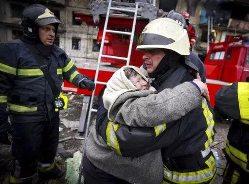 In this photo released by Ukrainian State Emergency Service, a firefighter hugs an elderly woman after evacuation from an apartment building hit by shelling in Kyiv, Ukraine, Monday, March 14, 2022. (Ukrainian State Emergency Service via AP)