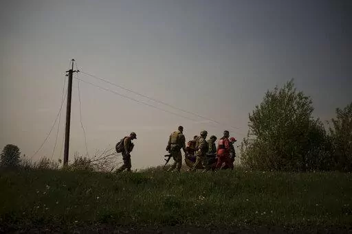 Ukrainian servicemen and emergency workers carry the body of a suspected Russian soldier in Malaya Rohan, a village retaken by Ukrainian forces on the outskirts of Kharkiv, Ukraine, Sunday, May 8, 2022. (AP Photo/Felipe Dana)