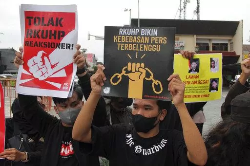 Activists hold up posters during a rally against Indonesia's new criminal law in Yogyakarta, Indonesia, Tuesday, Dec. 6, 2022. The country's parliament passed the long-awaited and controversial revision of its penal code Tuesday that criminalizes extramarital sex for citizens and visiting foreigners alike. Writings on the posters read "Reject the revised penal code" and "Revised criminal law shackles press freedom." (AP Photo/Slamet Riyadi)