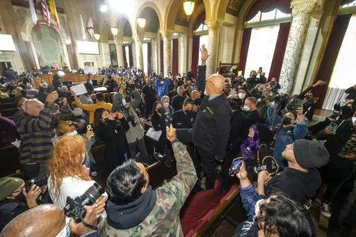 A man stands on the bench and shouts slogans during the Los Angeles City Council meeting Tuesday, Dec. 13, 2022, in Los Angeles. A small group of protesters chanted during the meeting calling for the resignation of Councilman Kevin de Leon. (AP Photo/Ringo H.W. Chiu)