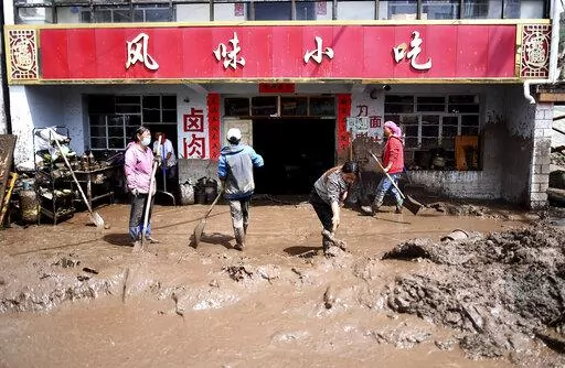 In this photo released by Xinhua News Agency, residents clear sludge from their property in the aftermath of floods in Qingshan Township of Datong Hui and Tu Autonomous County in northwest China's Qinghai Province on Thursday, Aug. 18, 2022. A sudden rainstorm in western China triggered a landslide that diverted a river and caused flash flooding in populated areas, killing some and leaving others missing, Chinese state media said Thursday. (Zhang Hongxiang/Xinhua via AP)