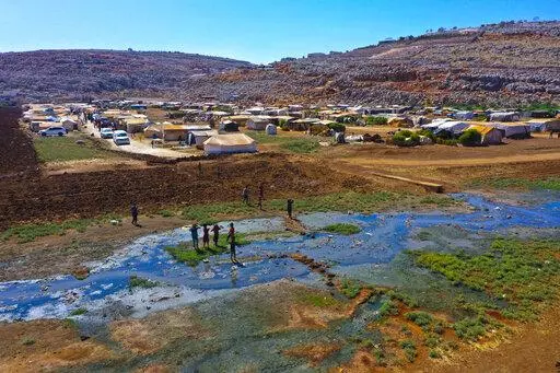 Children play near open sewage in the Salaheddine camp in northwestern Syria on Wednesday, Sept. 28, 2022. In recent weeks, thousands of cholera cases have swept across the crisis-stricken countries of Lebanon, Syria, and Iraq. (AP Photo/Ghaith Alsayed)