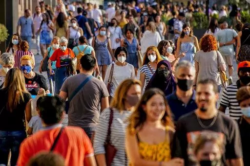 People wearing a face mask to protect against the spread of coronavirus walk along a street in downtown Barcelona, Spain, July 3, 2021. Some European countries such as Spain are making tentative plans for when they might start treating COVID-19 as an "endemic" disease, but the World Health Organization and other officials have warned that the world is nowhere close to declaring the pandemic over. (AP Photo/Joan Mateu, File)