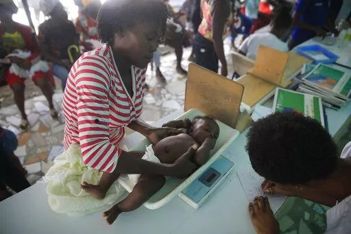 A health worker weighs a child at the Fontaine Hospital Center where the baby got multiple vaccinations during the visit in the Cité Soleil area of Port-au-Prince, Haiti, Monday, Jan. 23, 2023. As gangs tighten their grip on Haiti, many medical facilities in the Caribbean nation's most violent areas have closed, leaving Fontaine as one of the last hospitals and social institutions in one of the world's most lawless places. (AP Photo/Odelyn Joseph)