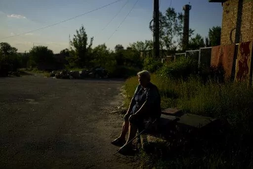 Olga Vasilyevna sits outside her home in Gorenka, on the outskirts of Kyiv,  Ukraine, Wednesday, June 8, 2022. Vasilyevna says that after attacks she still has no water nor electricity. (AP Photo/Natacha Pisarenko)