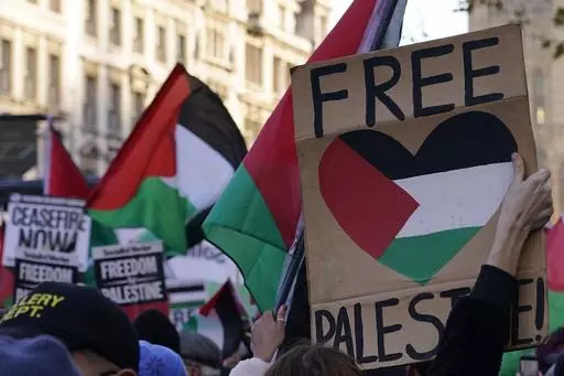 Protester hold flags and placards as they take part in a pro-Palestinian demonstration as they wend their way along Whitehall in London, Saturday, Nov. 25, 2023. (AP Photo/Alberto Pezzali)