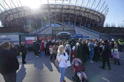 Hundreds of refugees from Ukraine wait in line to apply for Polish ID numbers that will entitle them to work, free health care and education, at a special application point at the National Stadium in Warsaw, Poland, on Saturday, March 19, 2022. The application points are not able to handle all those interested and ask many of them to return. (AP Photo/Czarek Sokolowski)