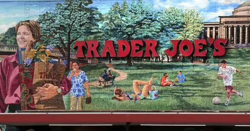 The Trader Joe's logo hangs on a mural, Aug. 13, 2019, in Cambridge, Mass. Trader Joe's recently upped the price to 23 cents for a single banana, marking a 4-cent increase from the grocer's previous going rate for the fruit that remained unchanged for over 20 years. (AP Photo/Charles Krupa, File)