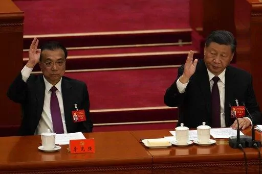 Chinese President Xi Jinping looks over as Chinese Premier Li Keqiang raises his hand to vote at the closing ceremony of the 20th National Congress of China's ruling Communist Party at the Great Hall of the People in Beijing, Saturday, Oct. 22, 2022. Chinese Premier Li Keqiang, the nation's No. 2 official and a chief proponent of economic reforms, is among four of the seven members of the nation's all-powerful Politburo Standing Committee who will not be reappointed in a leadership shuffle Sunda