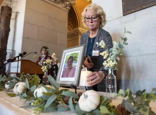Tracy Wodatch, from Connecticut Association for Healthcare at Home, places a candle next to a photo of Joyce Grayson during the lighting of the candles at a vigil for Grayson at the Connecticut State Capitol's North Lobby on Tuesday, Nov. 28, 2023. , in Hartford, Conn. The death of the 63-year-old mother of six is sparking renewed calls to better protect health care workers from a wave of violent attacks across the country.(Aaron Flaum/Hartford Courant via AP)