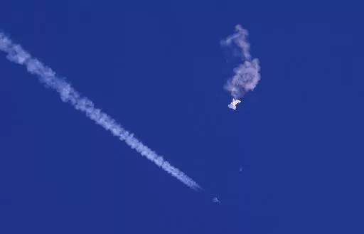 A fighter jet flies past the remnants of a large balloon after it was shot down above the Atlantic Ocean, just off the coast of South Carolina near Myrtle Beach, Feb. 4, 2023. The Defense Department and the Federal Aviation Administration have been tracking a balloon that was flying off the coast of Hawaii last week. A defense official says there’s no indication it is connected to China or any other adversary, and it presents no threats to aviation or national security. (Chad Fish via AP, File