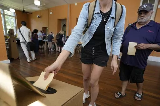 A man, right, waits as a woman drops her ballot into a box a polling place in Redfern as Australians cast their final votes in Sydney, Saturday, Oct. 14, 2023, in their first referendum in a generation that aims to tackle Indigenous disadvantage by enshrining in the constitution a new advocacy committee. Australia will look for new ways to lift Indigenous living standards after voters soundly rejected a proposal to create a new advocacy committee, the deputy prime minister said on Sunday, Oct. 1