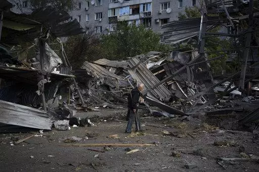An elderly man walks past a car shop that was destroyed after a Russian attack in Zaporizhzhia, Ukraine, Tuesday, Oct. 11, 2022. (AP Photo/Leo Correa)